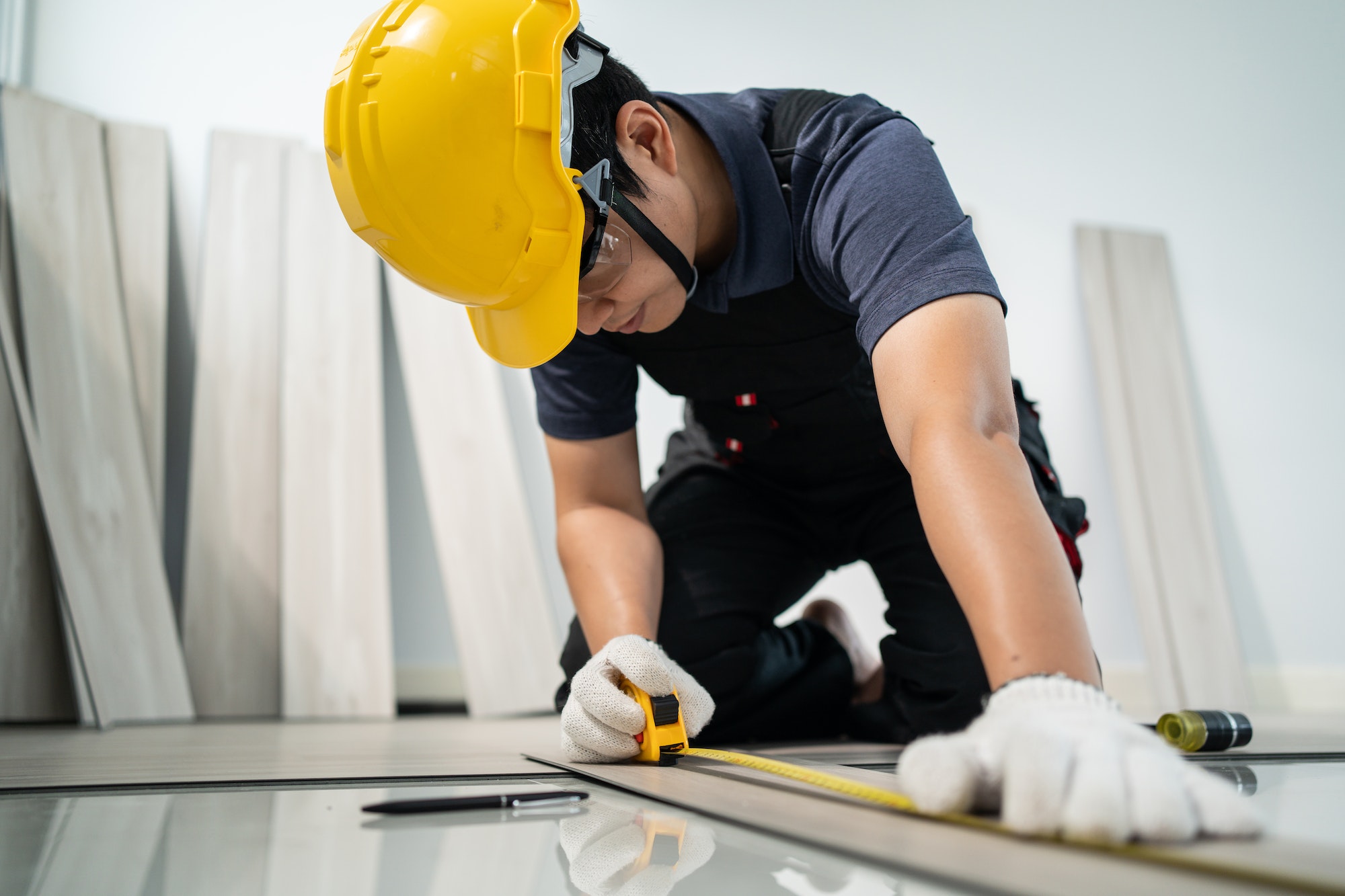 Asian Craftsman worker man use tape measure parquet on corridor to install laminate board on floor